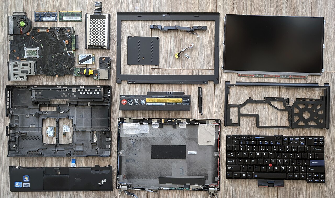 Laptop disassembled with its components laid out on a workbench